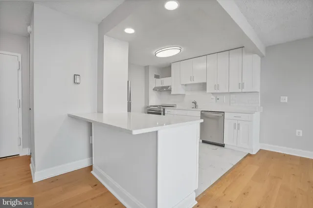 a kitchen with a sink cabinets stainless steel appliances and view living room