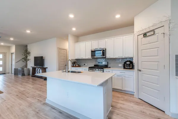 a large white kitchen with kitchen island a sink a stove a refrigerator and cabinets
