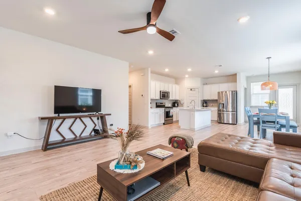 a living room with furniture and kitchen view with wooden floor