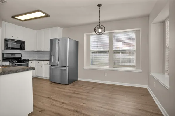 a kitchen with stainless steel appliances granite countertop a refrigerator a stove and a wooden floors
