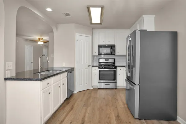 a kitchen with granite countertop a refrigerator stove and sink