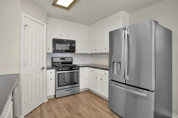 a kitchen with stainless steel appliances white cabinets and a refrigerator