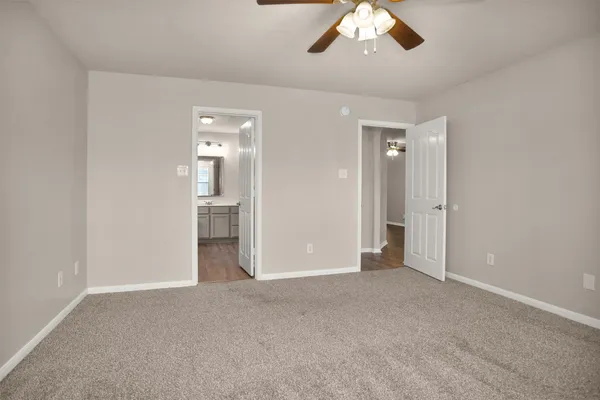 an empty room with chandelier fan and windows