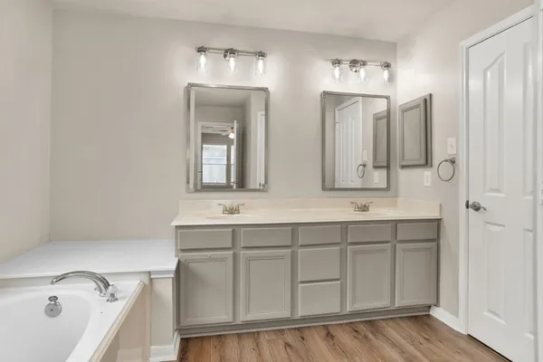 a bathroom with a double vanity sink mirror and bathtub
