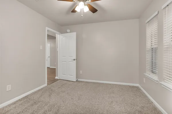 an empty room with a ceiling fan and carpet