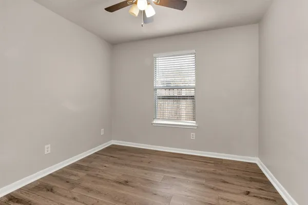 an empty room with wooden floor chandelier fan and window