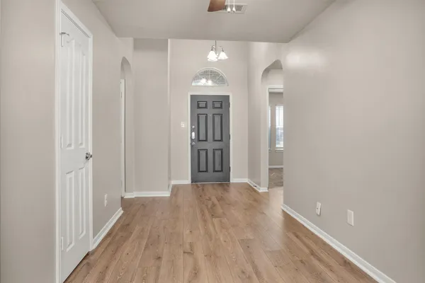 a view of a hallway with wooden floor and a bathroom