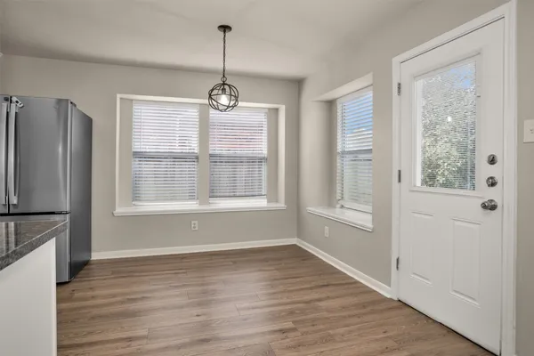 a view of an empty room with a window and wooden floor