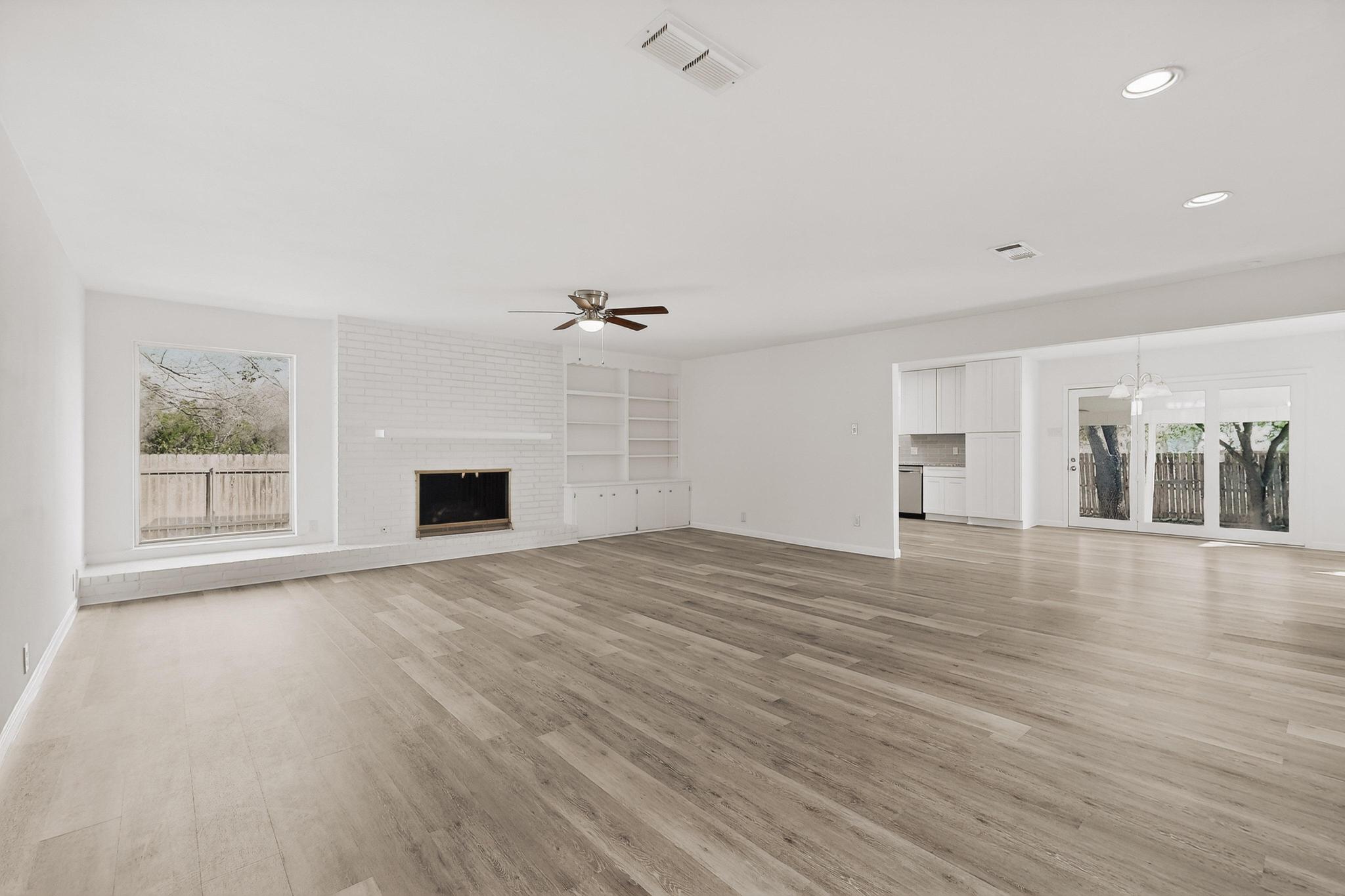 812 George Street Taylor, TX 76574 - Photo 9 of 34 Unfurnished living room featuring plenty of natural light, ceiling fan, a fireplace, light wood-style flooring, and recessed lighting