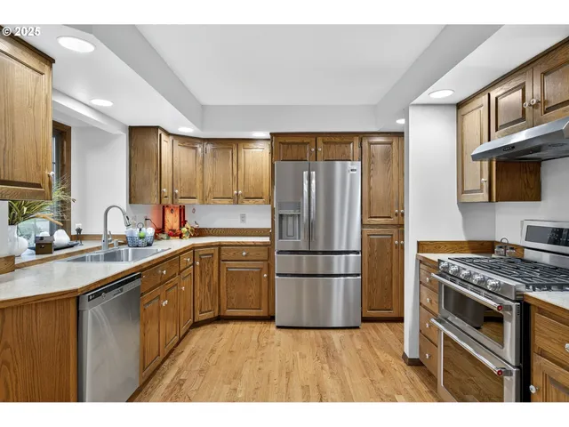 a kitchen with granite countertop a refrigerator stove top oven a sink and dishwasher