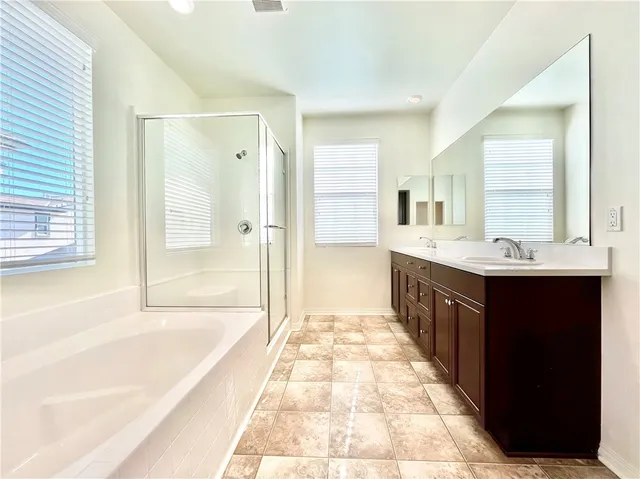 a spacious bathroom with a shower a sink and a mirror