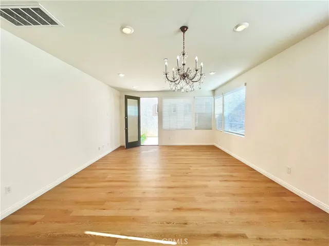 a view of empty room with wooden floor and chandelier