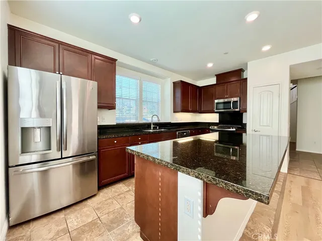 a kitchen with stainless steel appliances granite countertop a refrigerator a sink a stove a microwave and island
