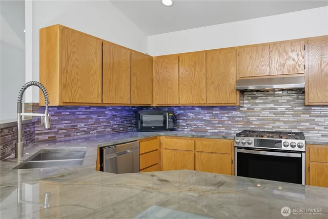 a kitchen with stainless steel appliances granite countertop a stove a sink and a microwave