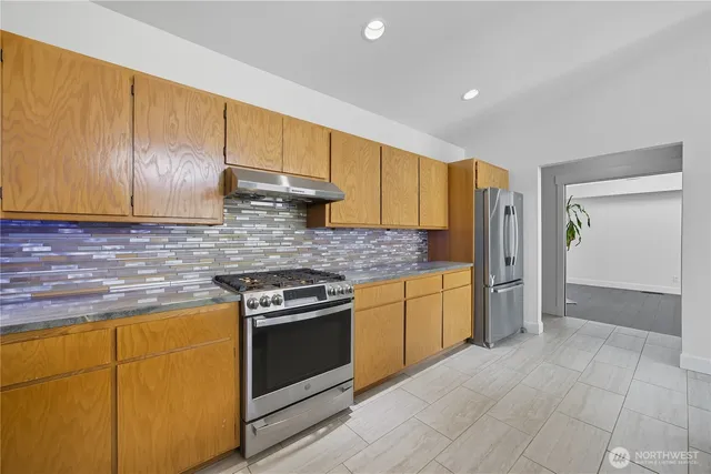a kitchen with stainless steel appliances granite countertop a stove a sink and a refrigerator
