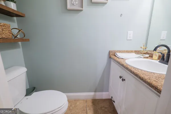 a bathroom with a granite countertop sink and a toilet