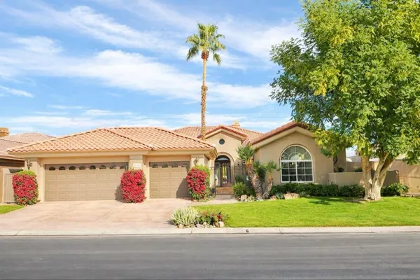 a front view of a house with a garden and mountain view