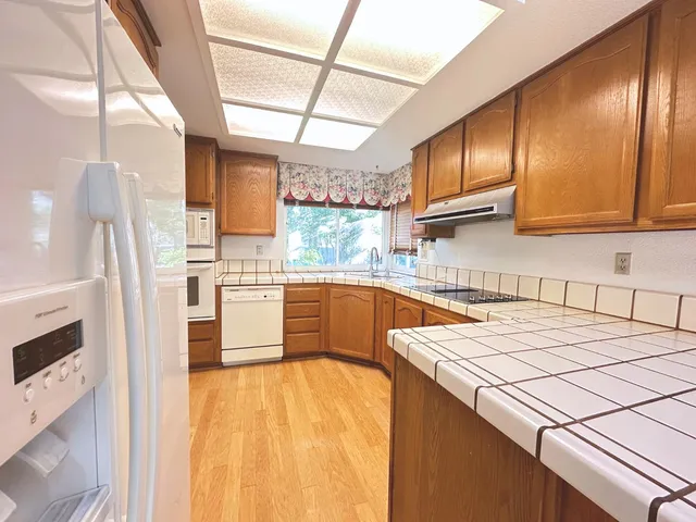 a kitchen with stainless steel appliances a sink a stove a refrigerator cabinets and a window
