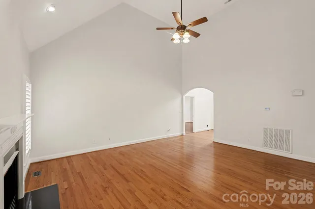an empty room with wooden floor fan and windows