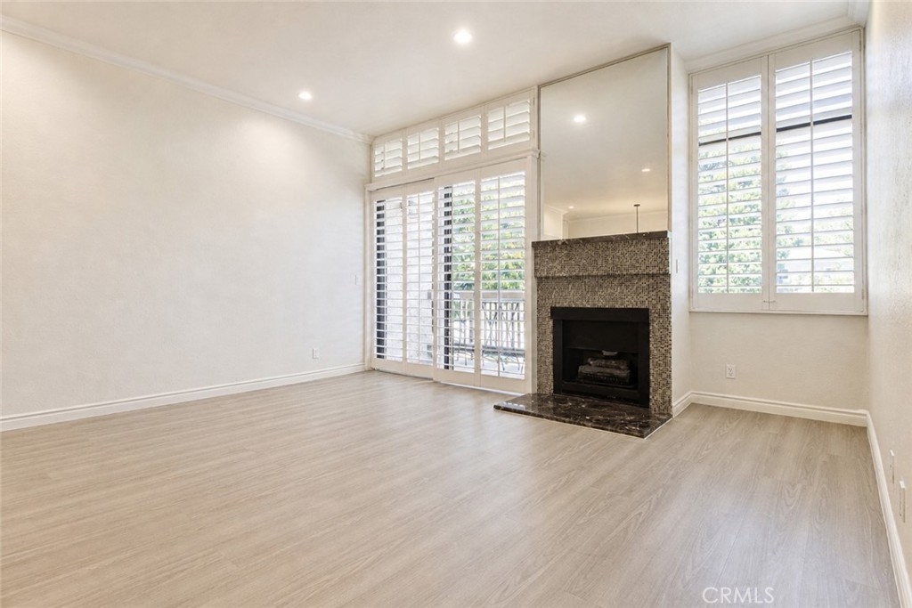 10470 Riverside Drive, Unit 102 Toluca Lake, CA 91602 - Photo 3 of 35 an empty room with wooden floor fireplace and windows