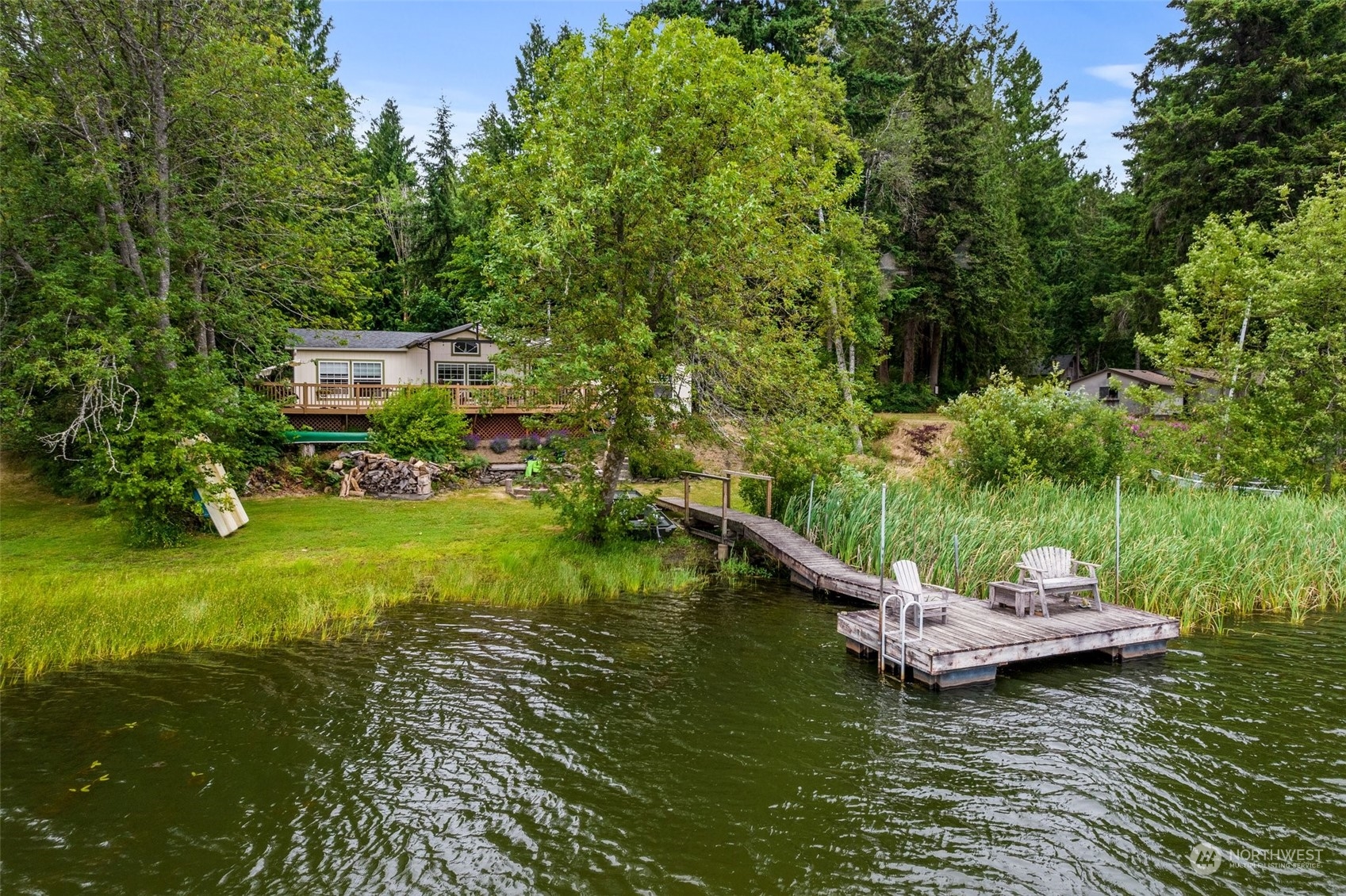 14940 Military Road Southeast Tenino, WA 98589 - Photo 3 of 30 a view of a lake with lawn chairs and large trees