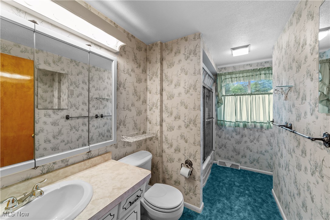 648 Rehwinkle Road Northfield, OH 44067 - Photo 23 of 38 Full bath featuring wallpapered walls, vanity, a shower stall, and a textured ceiling