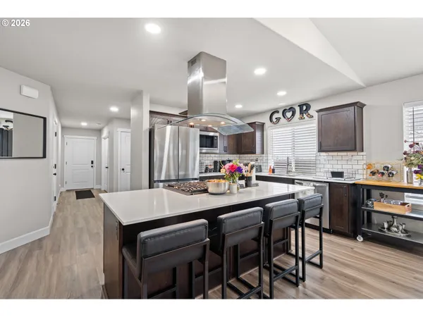 a kitchen with stainless steel appliances kitchen island granite countertop a dining table chairs and white cabinets