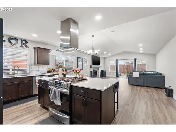 a kitchen with stainless steel appliances granite countertop a sink a stove and a wooden floors