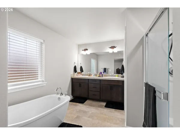 a bathroom with a bathtub a sink a vanity a window and a shower