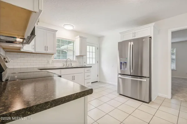 a kitchen with stainless steel appliances granite countertop a sink a microwave stove and white cabinets