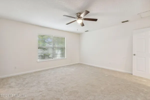 a view of an empty room and chandelier fan