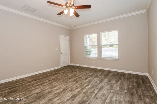 a view of an empty room with a window and a chandelier fan