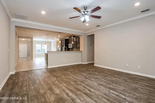 a view of a big room with wooden floor and a kitchen