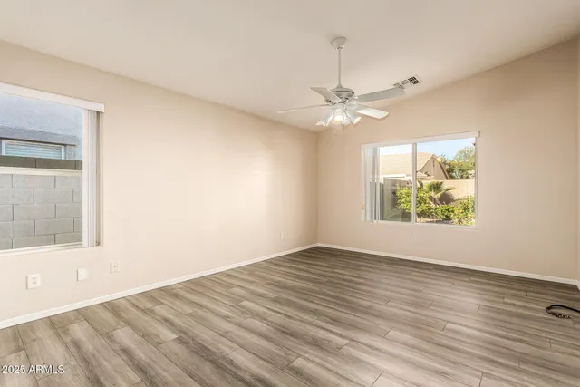 an empty room with wooden floor and windows