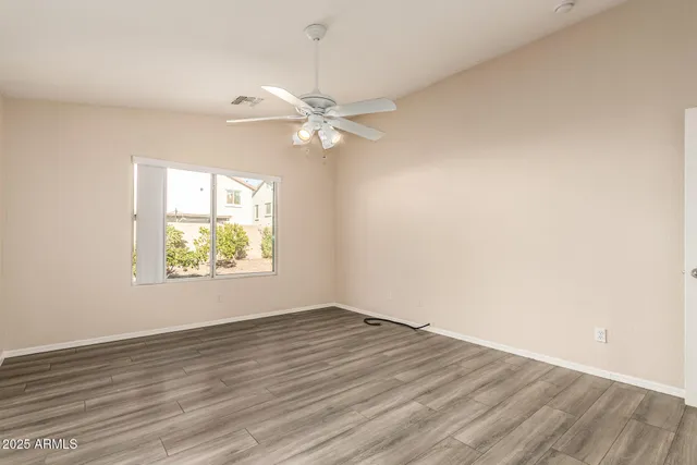 a view of an empty room with window and wooden floor