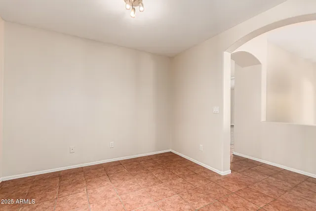 an empty room with kitchen entrance and wooden floor