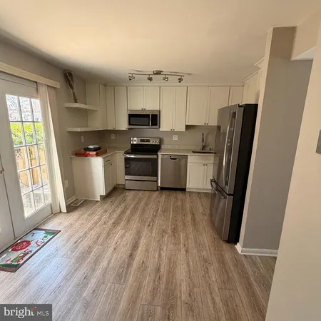 a kitchen with stainless steel appliances a refrigerator a sink dishwasher a stove top oven a refrigerator with wooden floor and cabinets