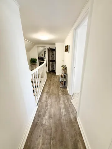 a view of a hallway with wooden floor and stairs