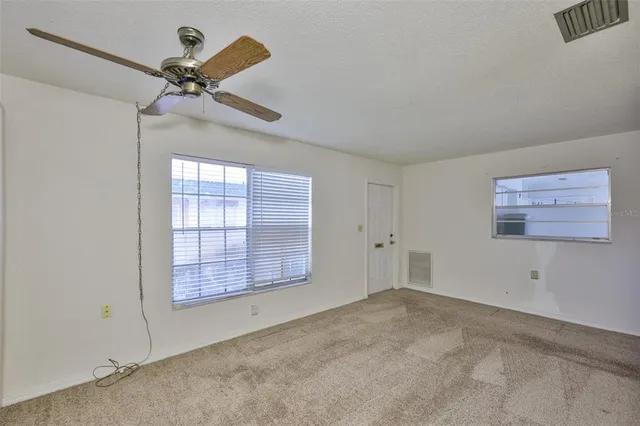 an empty room with windows and fan