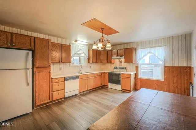 a large kitchen with a large counter top space a sink stainless steel appliances and cabinets