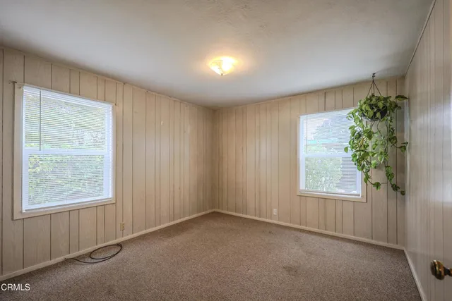 an empty room with windows and flower plants