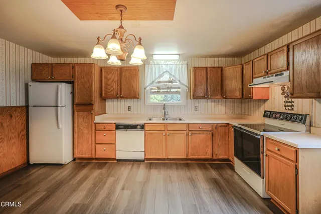 a kitchen with stainless steel appliances granite countertop a refrigerator a sink dishwasher a stove with wooden cabinets and floor