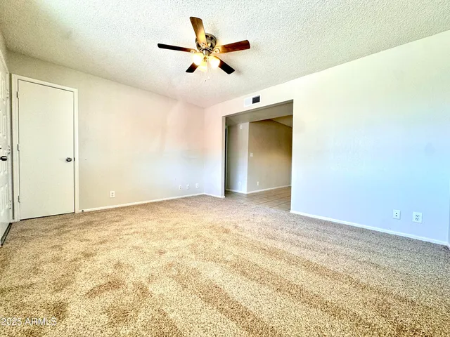an empty room with a ceiling fan and carpet