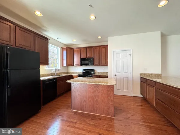 a kitchen with granite countertop a refrigerator stove top oven and sink