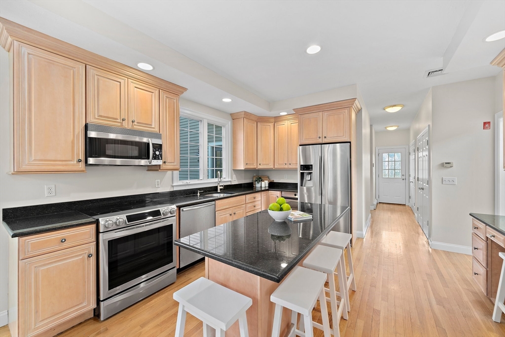 34 Forest Street Hanover, MA 02339 - Photo 4 of 42 a kitchen with stainless steel appliances granite countertop a refrigerator a stove top oven a sink dishwasher and white cabinets with wooden floor