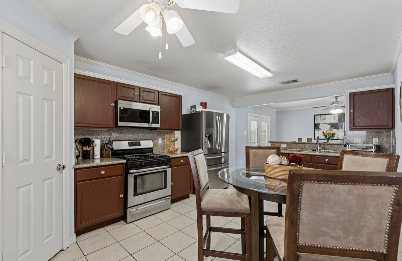 7118 Rising Brook Drive Cypress, TX 77433 - Photo 10 of 21 a kitchen with stainless steel appliances granite countertop a stove top oven a sink dishwasher a dining table and chairs with wooden floor