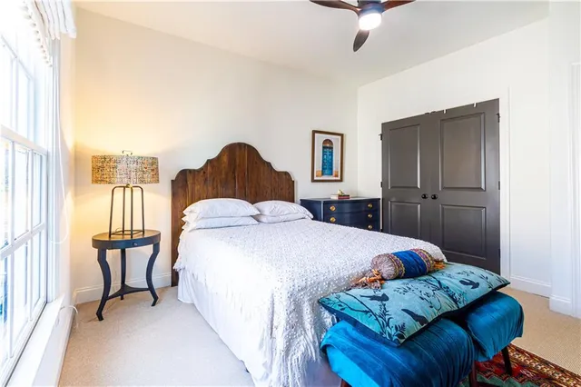 a bed sitting in a bedroom next to a window with a chandelier