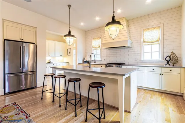 a kitchen with stainless steel appliances granite countertop a sink a stove a refrigerator and island with wooden floor