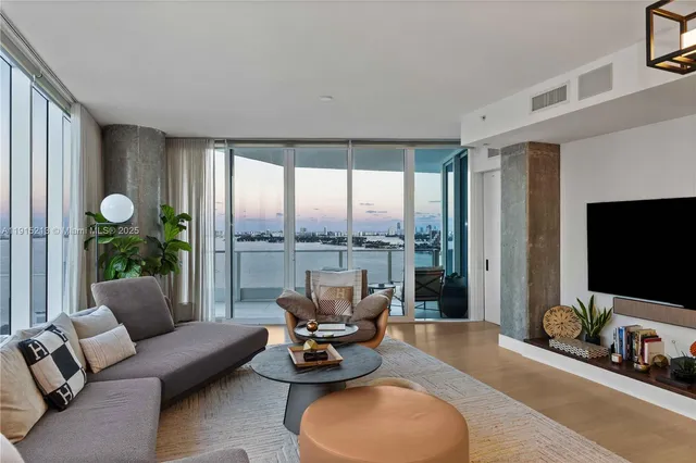 a living room with furniture floor to ceiling window and a flat screen tv