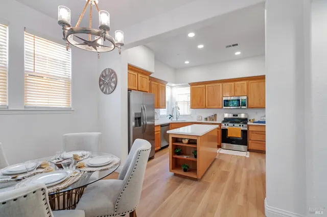 a room with stainless steel appliances a table and chairs
